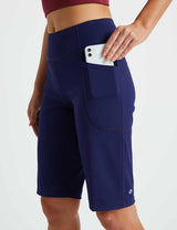 Navy blue women's 12" high-waisted running shorts with pockets, one holding a smartphone.