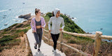 Women jogging coastal stairs in sun-protective activewear