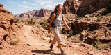 Woman hiker in light pants walking through a sunny red rock canyon