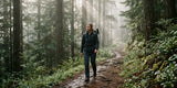 Woman hiking in full-length pants with a backpack on a misty forest trail