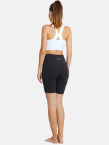 Woman wearing dark gray 7" high waist Baleaf yoga shorts and white sports bra, back view. #color_Gray