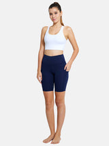Navy blue 7" yoga high waist comfort shorts with pockets, worn by a model in a white sports bra. #color_Blue