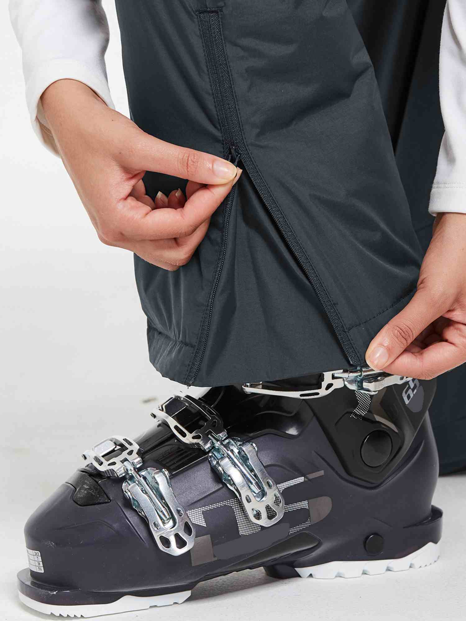 Dark grey waterproof ski bib pants zipper detail with ski boot