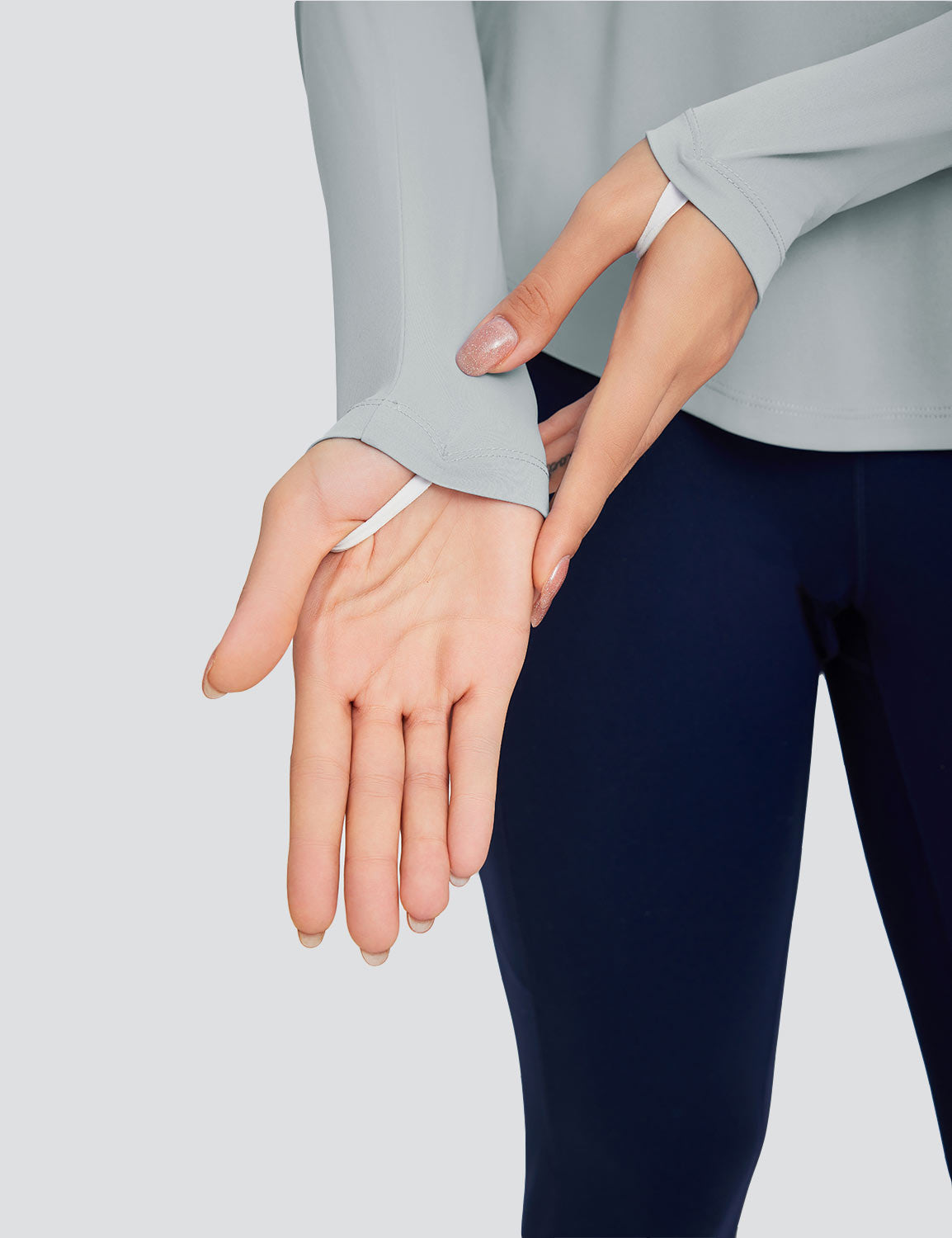 Light gray crew neck long sleeve t-shirt with thumbholes, worn with navy blue leggings.