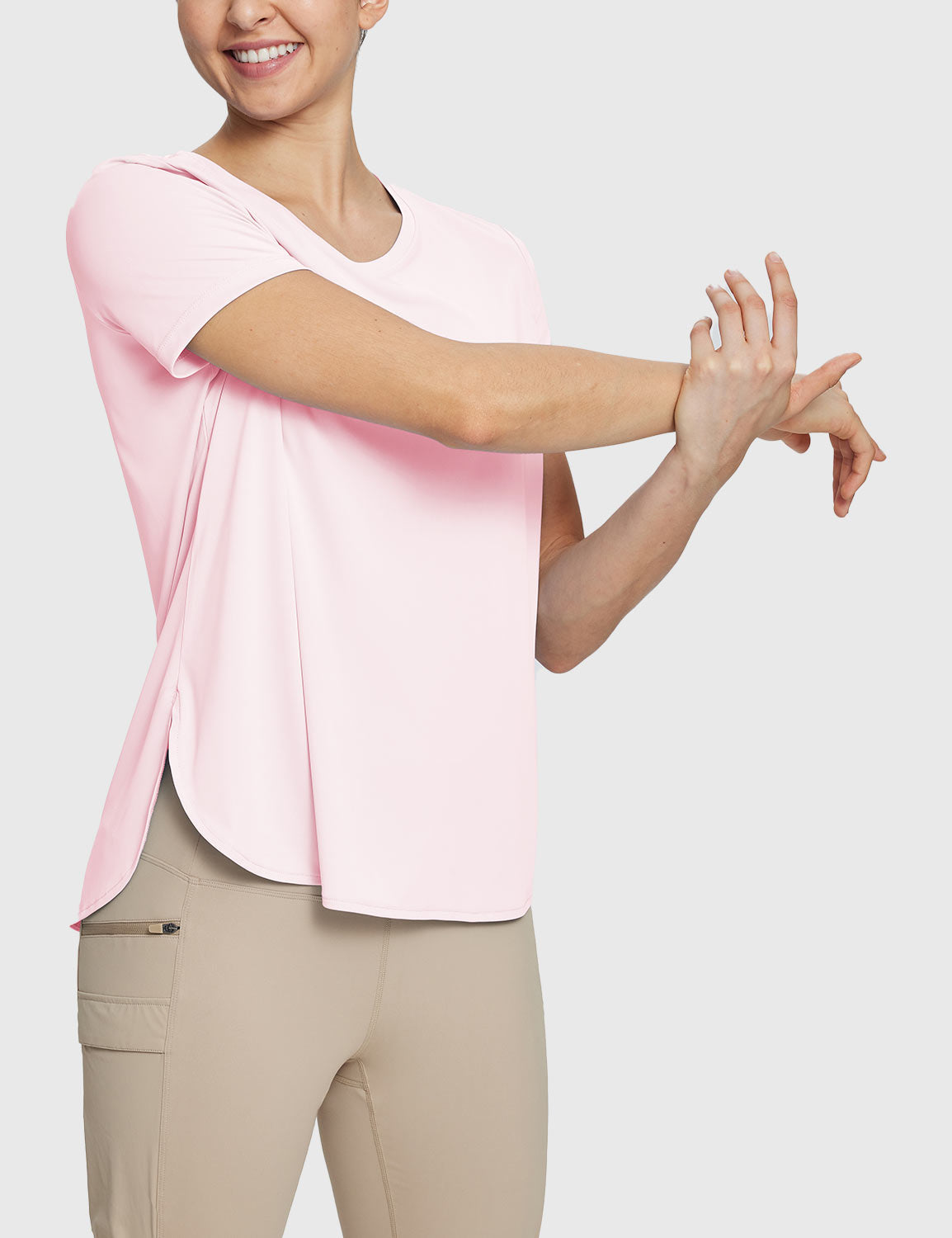 Woman in pink UPF 50+ tee and khaki trail shorts, stretching comfortably. #color_Pink