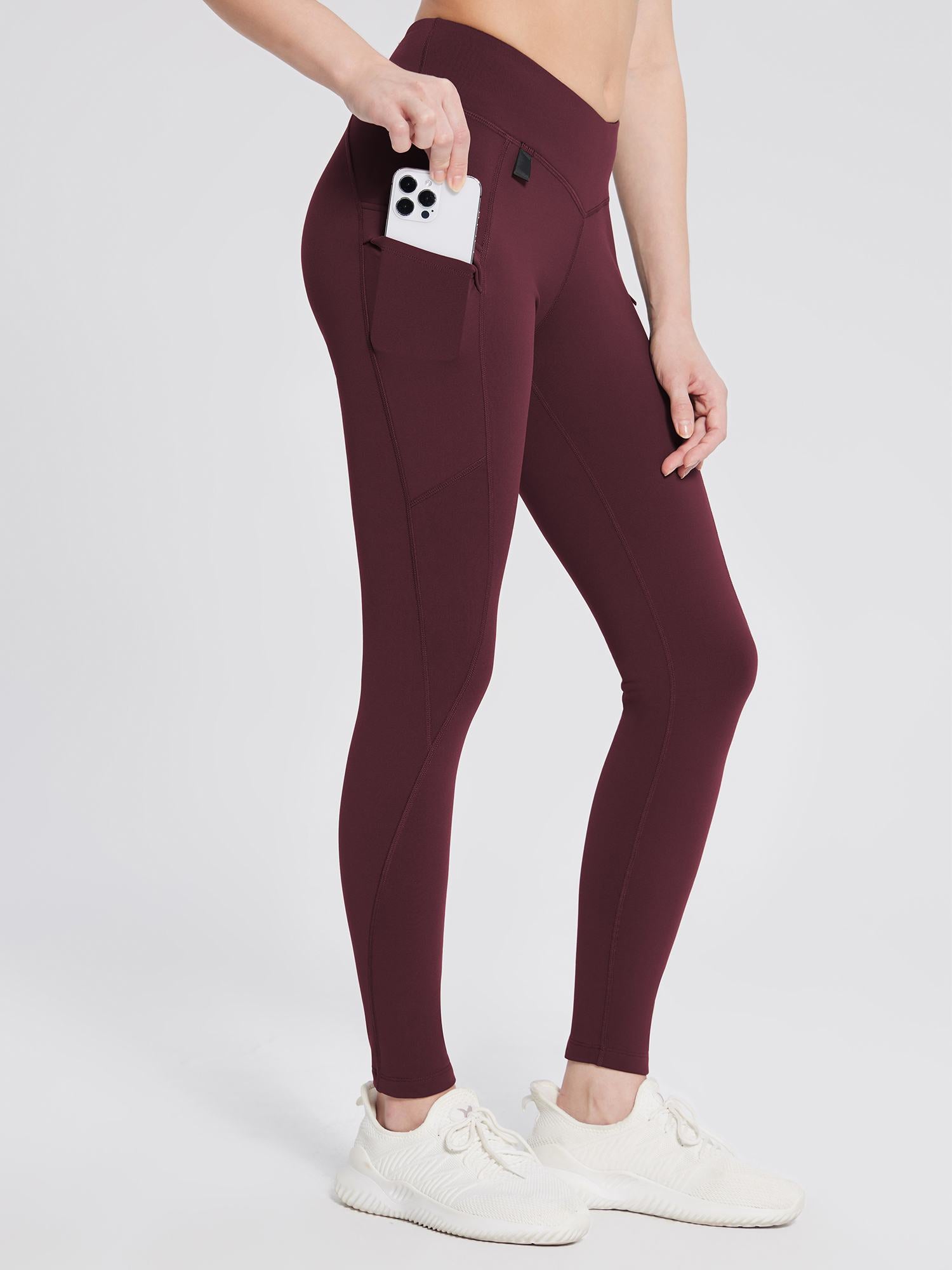 Burgundy fleece-lined hiking leggings with V-waist and side pocket holding smartphone. #color_Wine Red