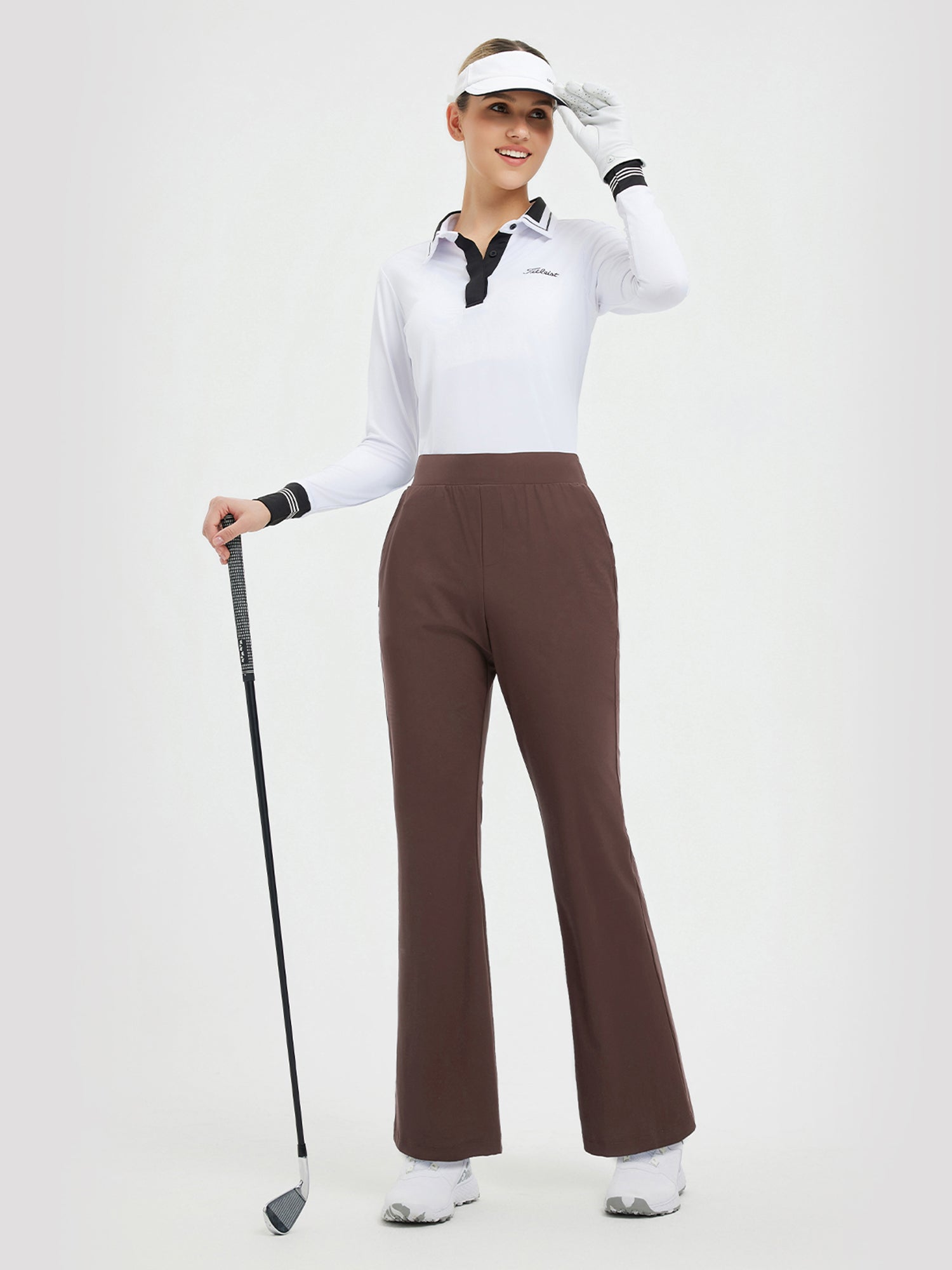 Women's brown 29" flare golf pants, styled with white Titleist polo shirt and visor. #color_Dark Brown