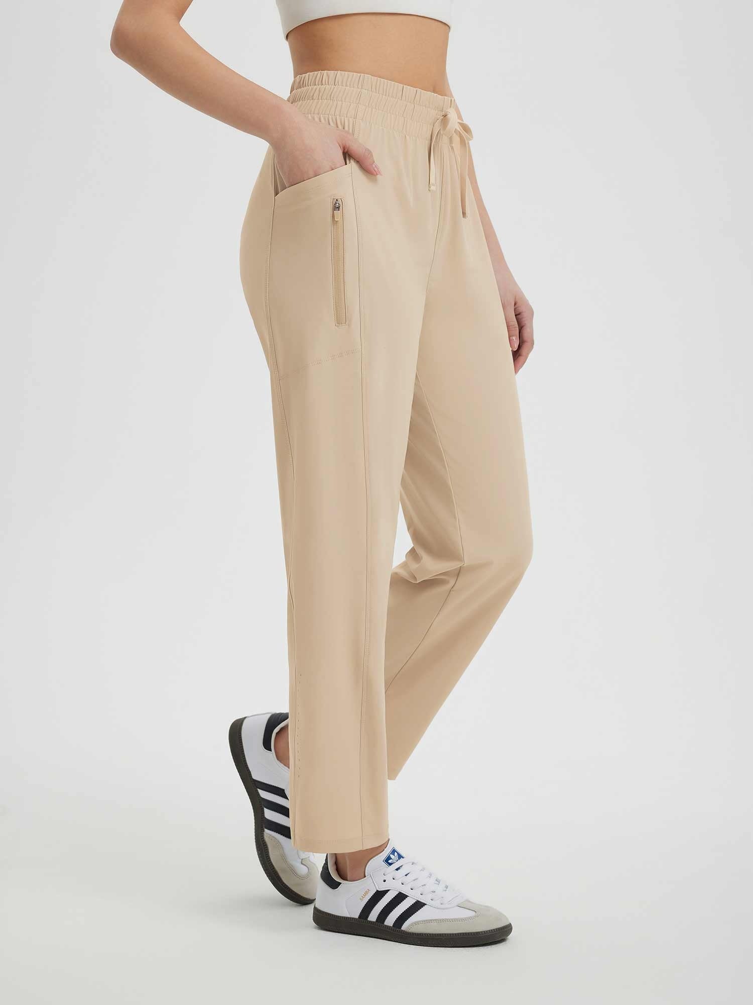 Beige women's running sweatpants with elastic waist, drawstring, side pocket, and zipper pocket. #color_Khaki