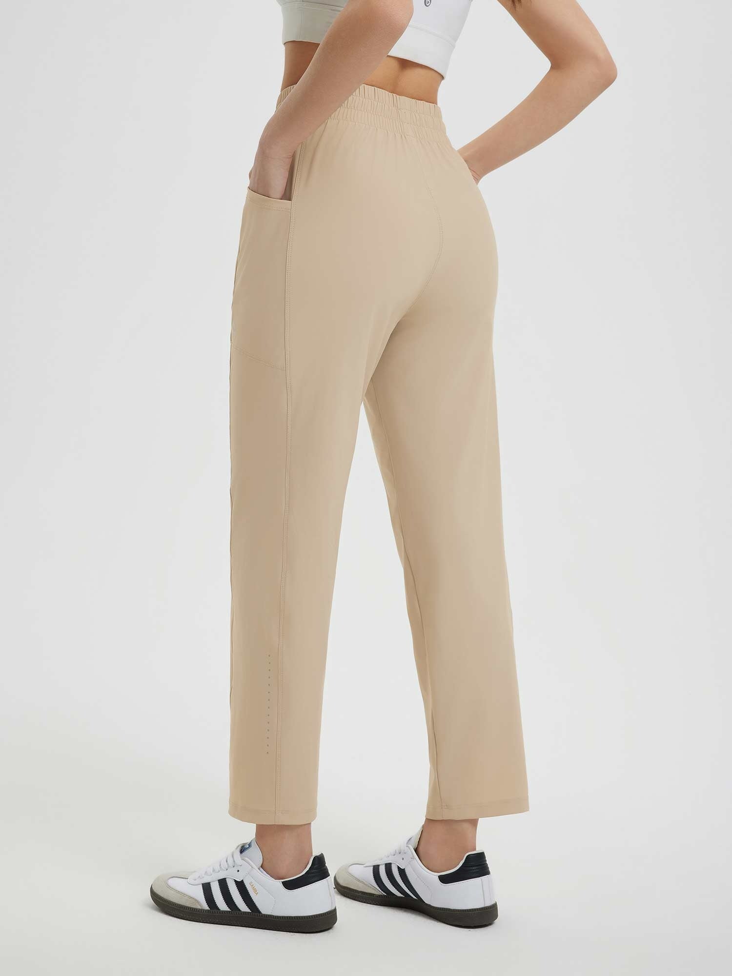 Women's light beige running sweatpants: quick-drying fabric, elastic waist, utility pockets.