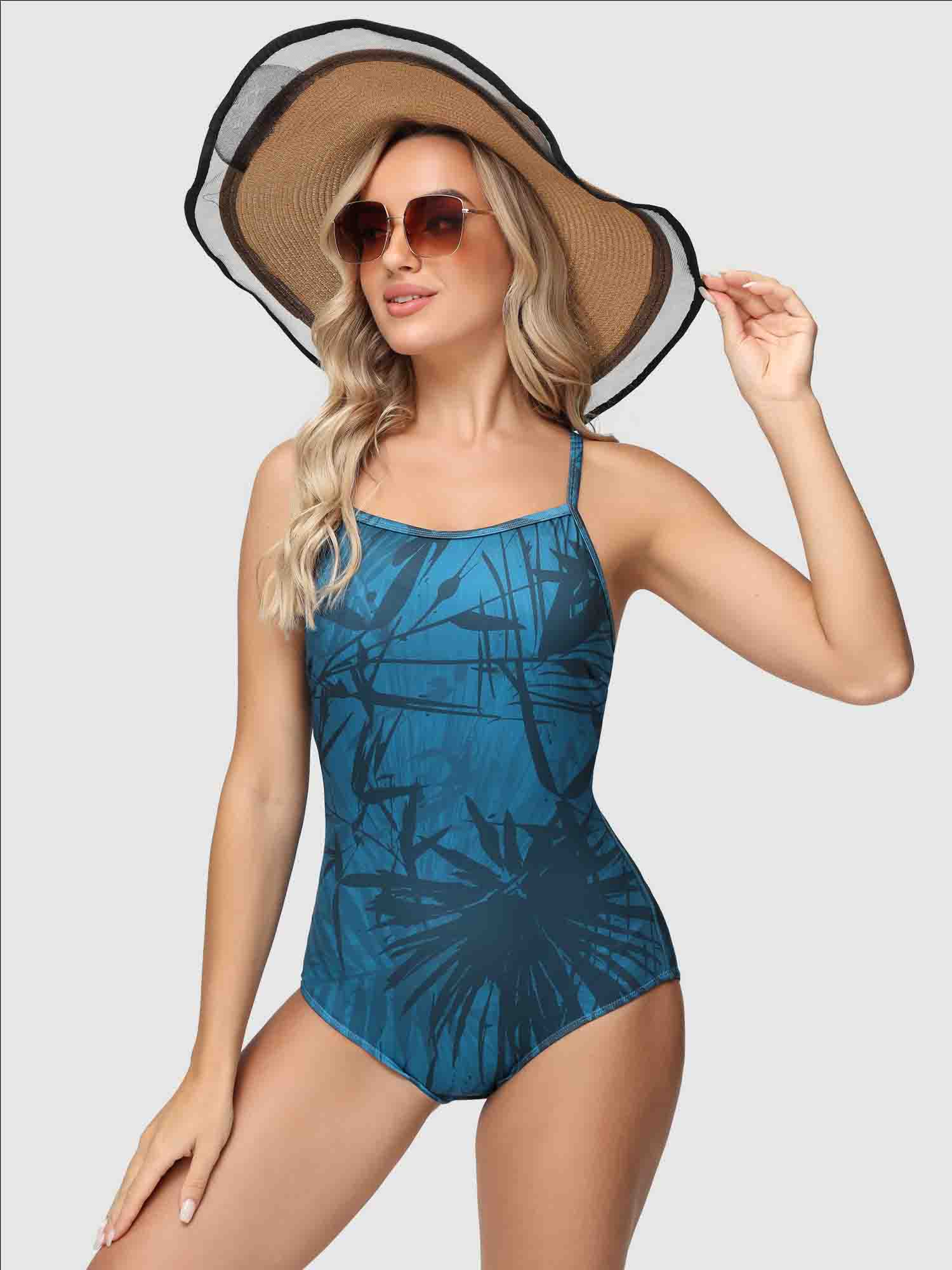 Women's blue one-piece swimsuit with a dark tropical leaf print and adjustable straps. #color_Peacock