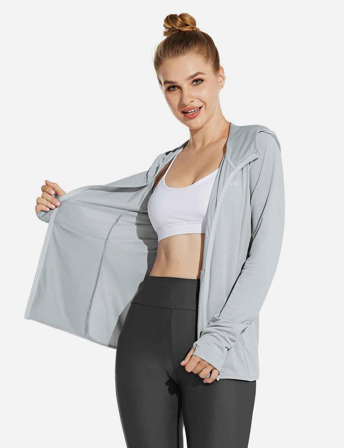 Light gray Laureate UPF 50+ cooling zip-up jacket on woman with white sports bra and dark gray leggings. Features thumbholes.