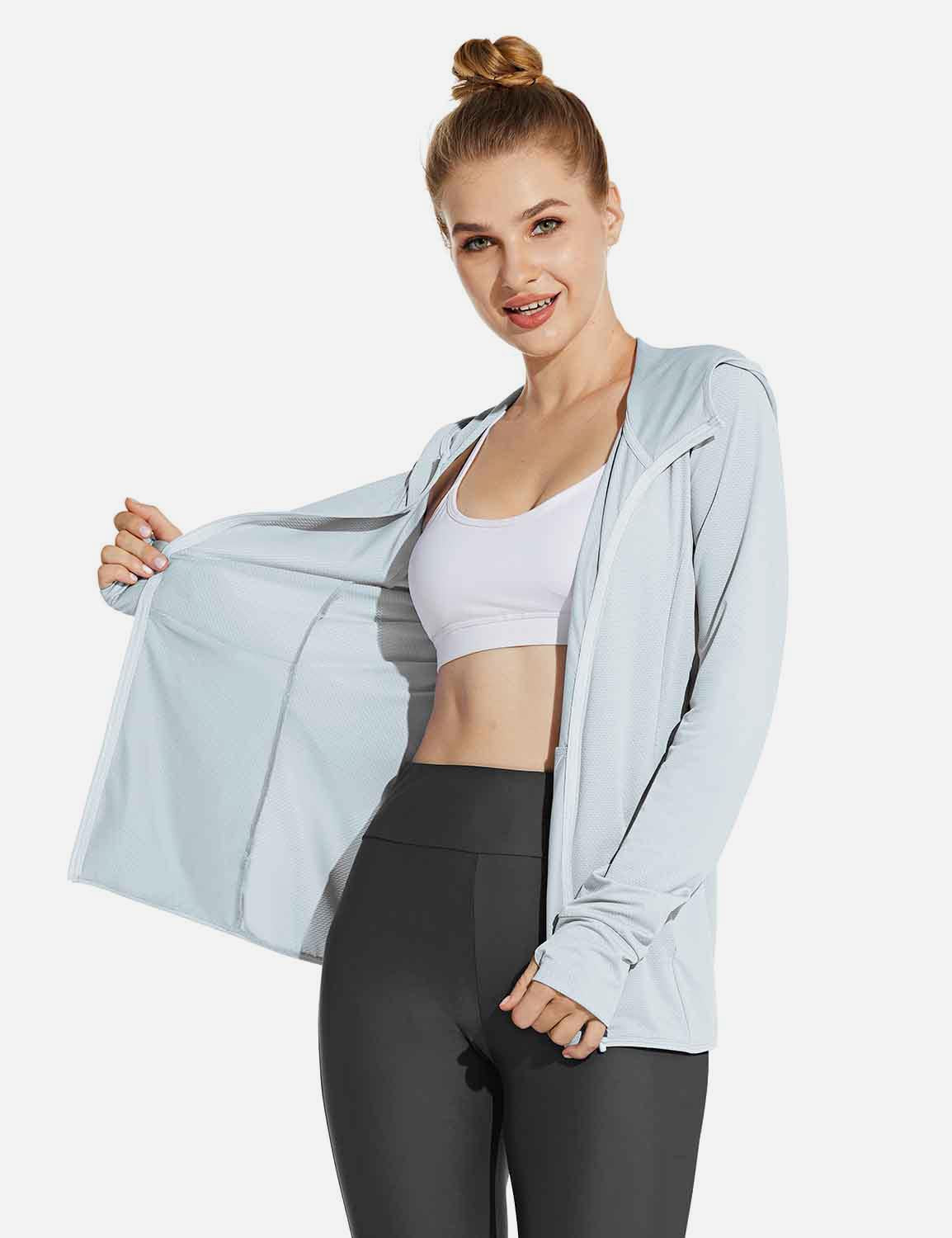 Light blue Laureate UPF 50+ cooling zip-up jacket on woman. Features thumbholes, open front over white sports bra and dark leggings.