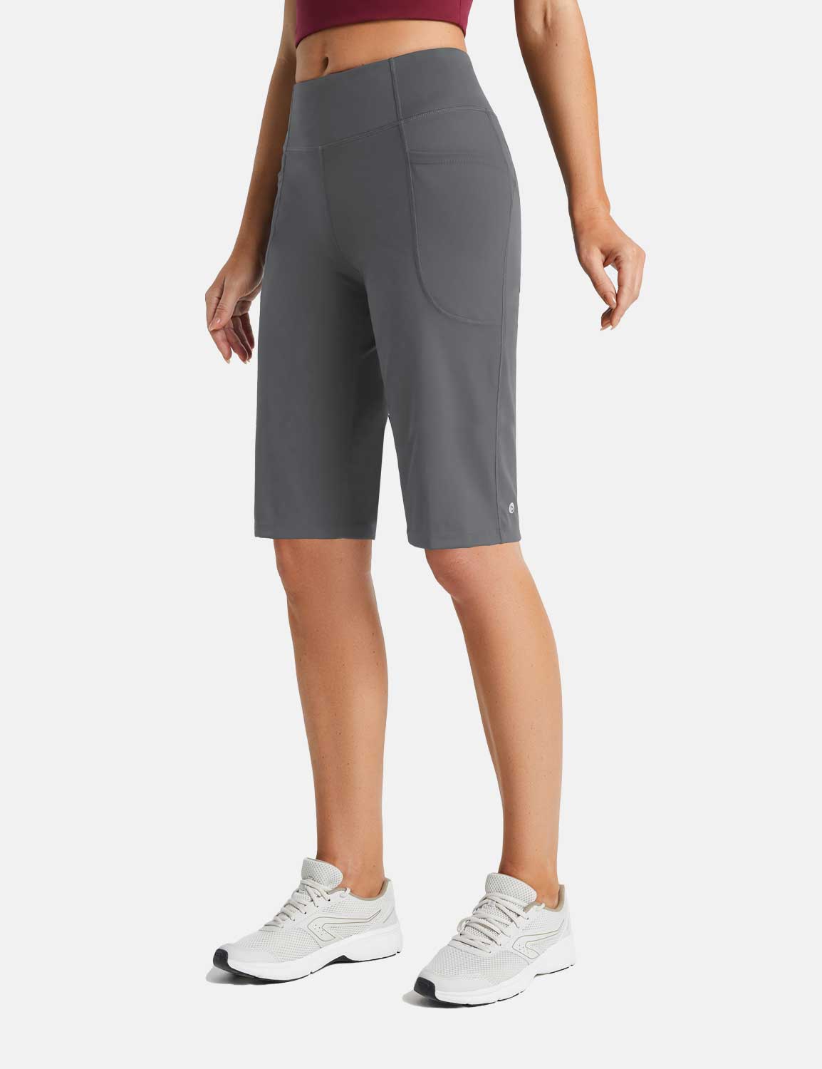 Woman wearing gray high-waisted 12" running shorts with side pockets and white sneakers.