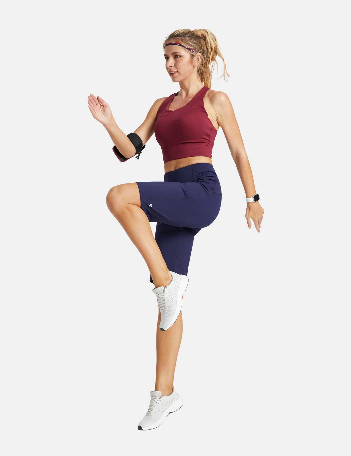 Woman in navy high-waisted running shorts and burgundy sports bra in motion